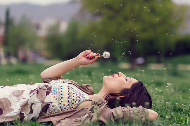 istock Woman blowing dandelion in the park with copyspace 529061538