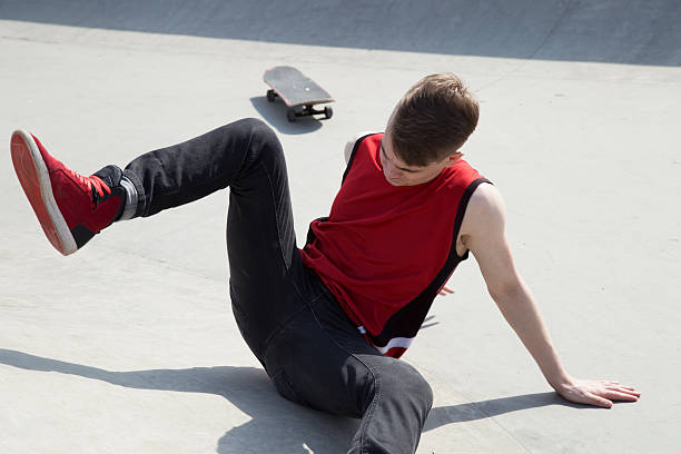 istock Young man fall off  skate board, sitting on concrete ramp. 529062604