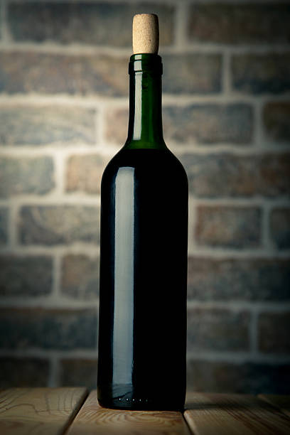 istock Wine bottle on a wooden table with bricks wall background 529064534