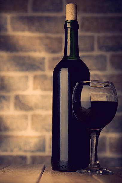 istock Wine bottle and glass on a wooden table bricks wall 529064734