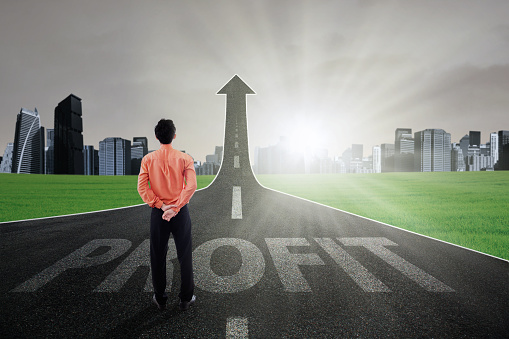 Businessman standing on the highway going up as an arrow with Profit text, symbolizing growth profit