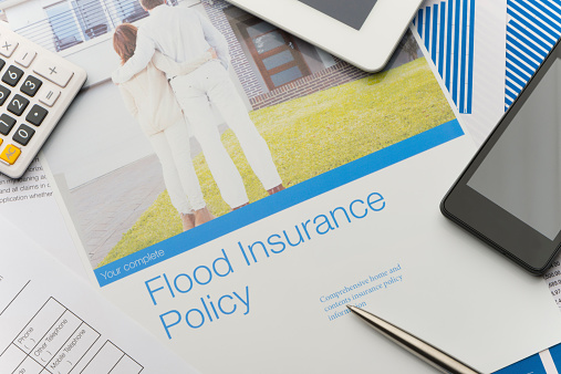 Flood insurance policy brochure with image of a couple in front of a house. Cover of a brochure with technology. Mobile phone, digital tablet and calculator. Image on brochure is fully released and can be found in my portfolio. Image number 26822047