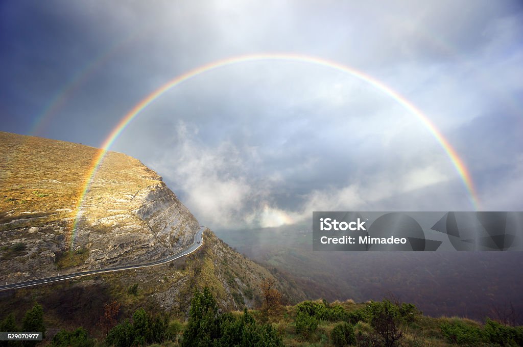 mountain pass road with stormy clouds and rainbow mountain pass road with stormy clouds and a rainbow Asphalt Stock Photo