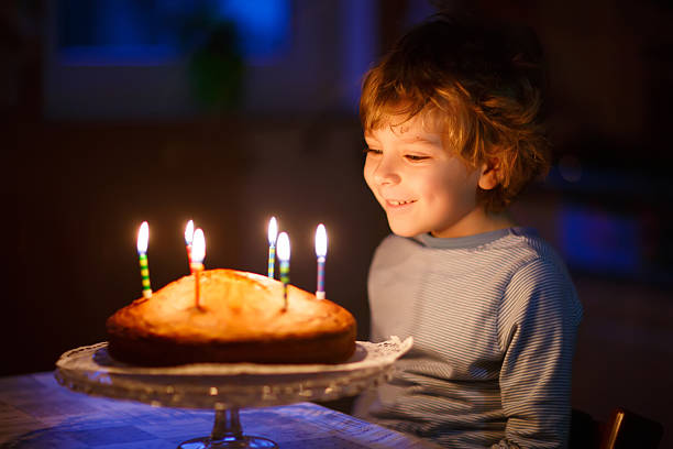 istock Little kid boy blowing candles on birthday cake 529071526