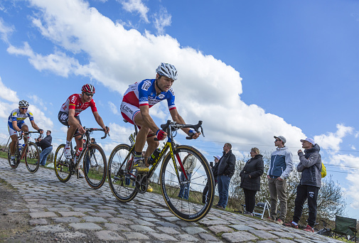 Hornaing ,France - April 10,2016: Group of three cyclists riding in the peloton on a paved road in Hornaing, France during Paris Roubaix on 10 April 2016.