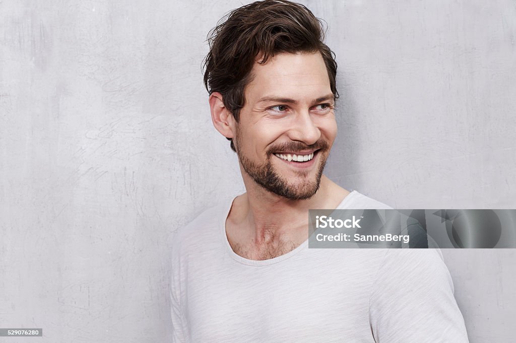 Smiling young man in studio, looking away Young Men Stock Photo