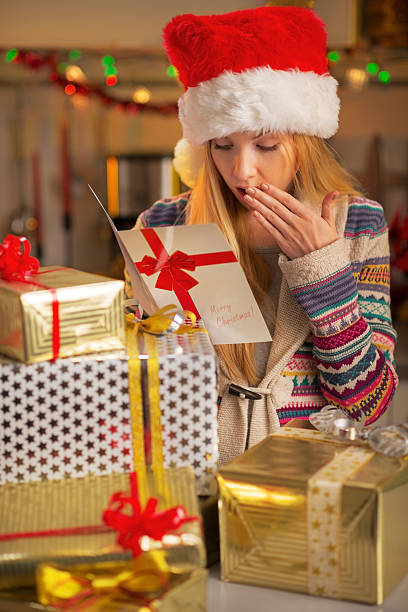 istock Teenager with stack of christmas present boxes reading postcard 529079773