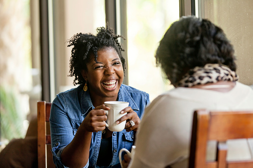 Attractive African American women have a good time with a close friend drinking good coffee.