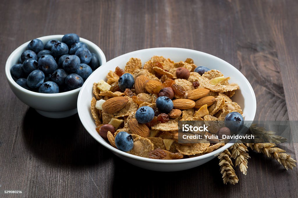 cereal flakes with blueberries and nuts on dark wooden table cereal flakes with blueberries and nuts on a dark wooden table, horizontal Berry Fruit Stock Photo