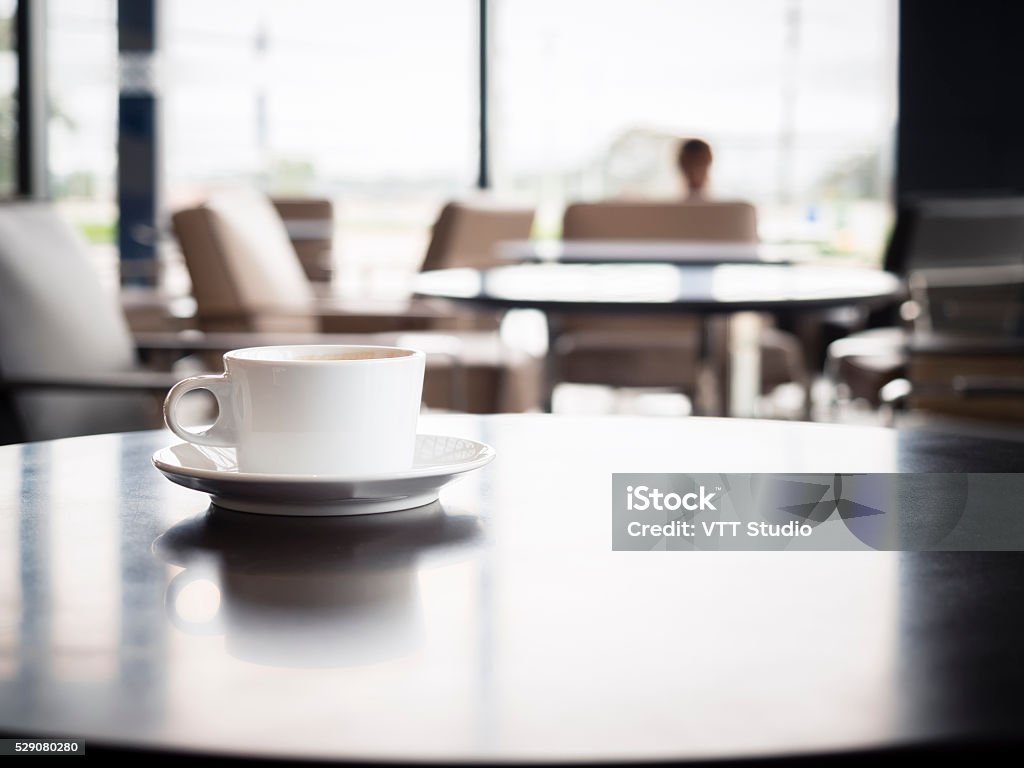 Coffee cup on table with blurred people in Restaurant Interior Coffee cup on table with blurred people in Restaurant shop cafe Interior seats background Airport Departure Area Stock Photo