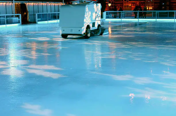 An ice resurfacing machine smoothes an illuminated ice rink in the middle of London.