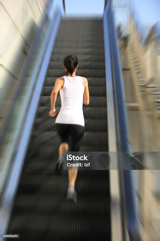 Runner athlete running on escalator stairs. Runner athlete running on escalator stairs. woman fitness jogging workout wellness concept. Active Lifestyle Stock Photo