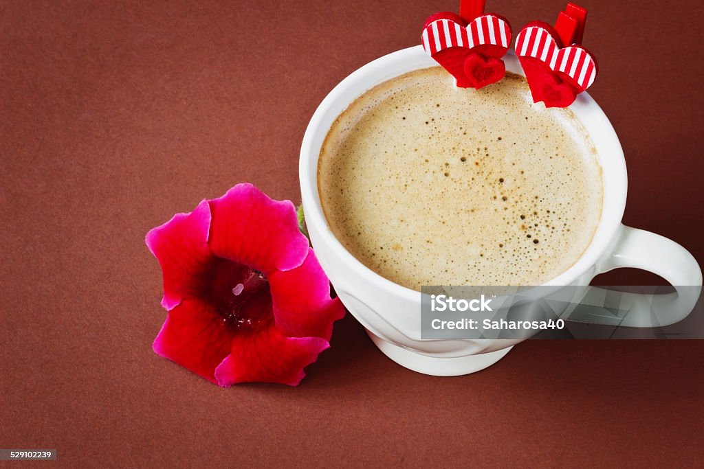 festive coffee cup of hot coffee, flowers and decorative valentine on a brown background. valentine's day. festivals and events. Brown Stock Photo