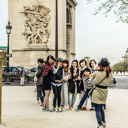 Paris, France - April 3, 2014: A group of asian tourists taking photos at the Arc de Triomphe in Paris, France.