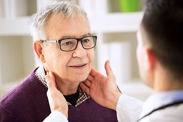 ancien médecin examine un patient lymphatique - throat photos et images de collection