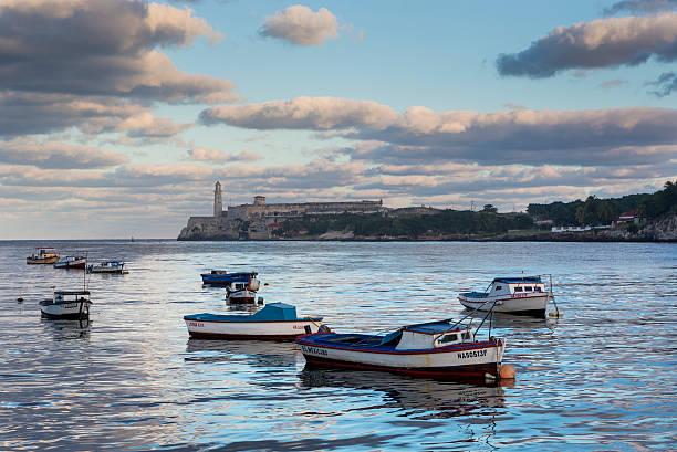 Havan Cuba Malecon El Morro fishing boats Havana, Cuba - November 11th, 2014:El Morro castle photographed from the seawall along the Avenida de Maceo, otherwise known as The Malecón. Local fishing boats are in the foreground.  morro castle havana stock pictures, royalty-free photos & images