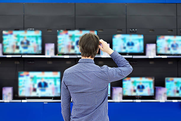 istock Man looks at LCD TVs in store 529117618
