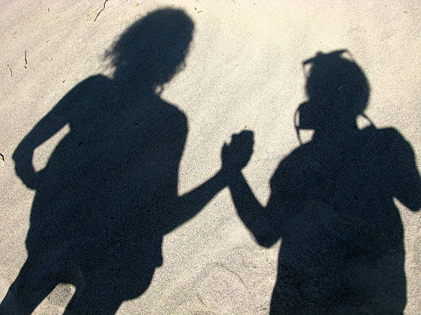 Blurry shadow silhouette of a little girl walking alone on a summer day with a family behind her