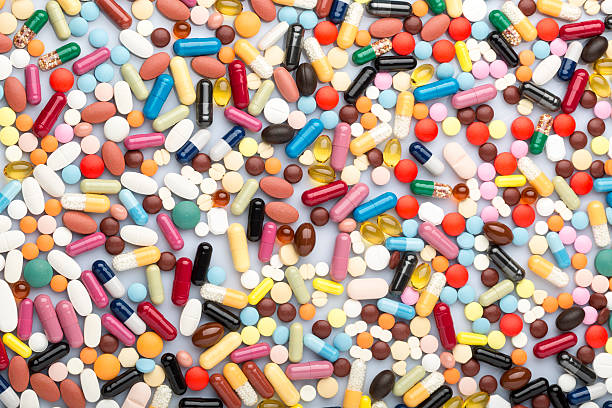 россыпь разноцветных медицинские таблетки и лекарственных препаратов - pill multi colored capsule nutritional supplement стоковые фото и изображения