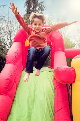 Small boy jumping down the slide on an inflatable bouncy castle