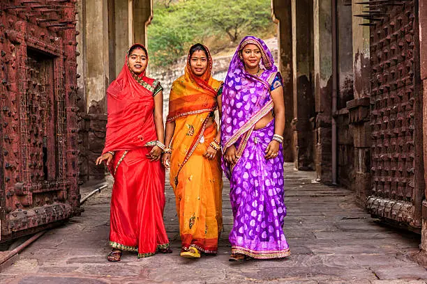 Three Indian women, wearing saris, are going up the way to Mehrangarh Fort near Jodhpur, Rajasthan. 