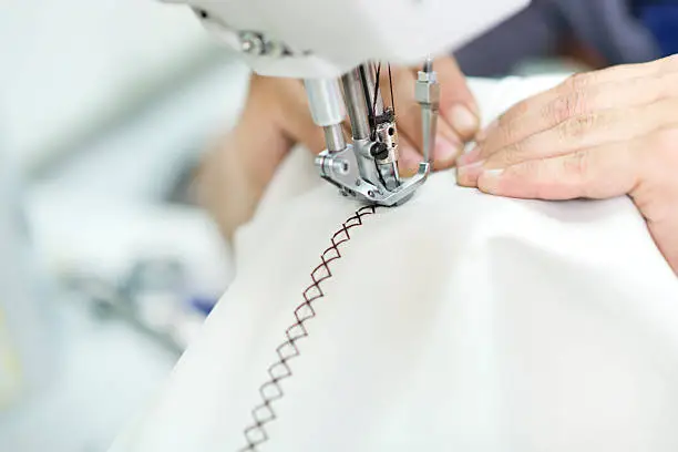 Tailor at Work on Industrial Sewing Machine with Presser Foot. White Eco Leather Fabric Texture with Stitching.