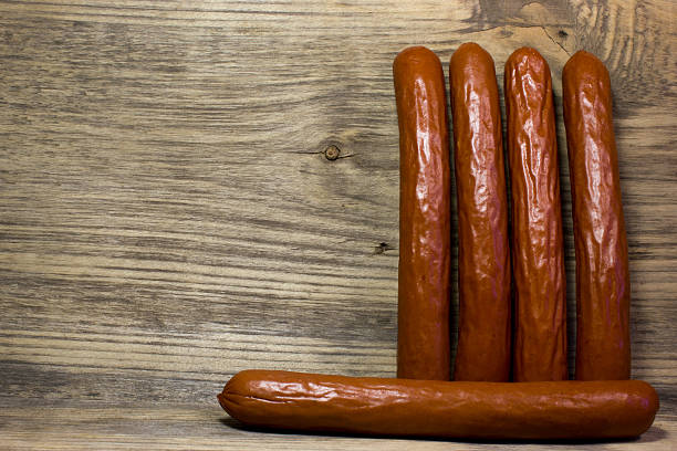 istock Smoked beer sausages on wooden background. 529127598
