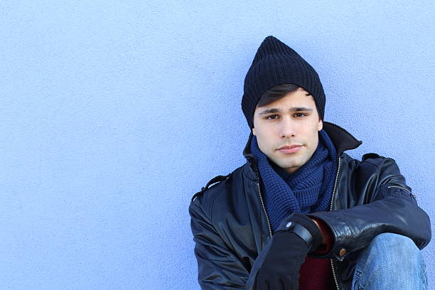 Fashion portrait hipster man freezes hides his head and warms body in winter city