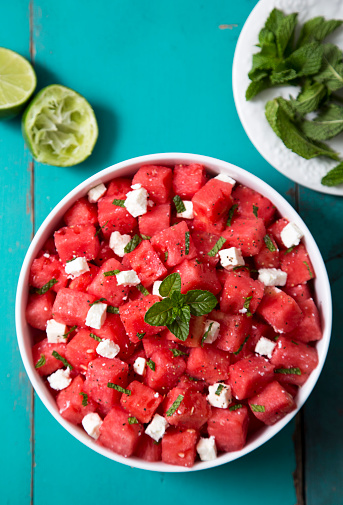 A watermelon feta and mint said with lime juice and olive oil on a vibrant aqua colored picnic table.   Please see my portfolio for other food and drink images. 