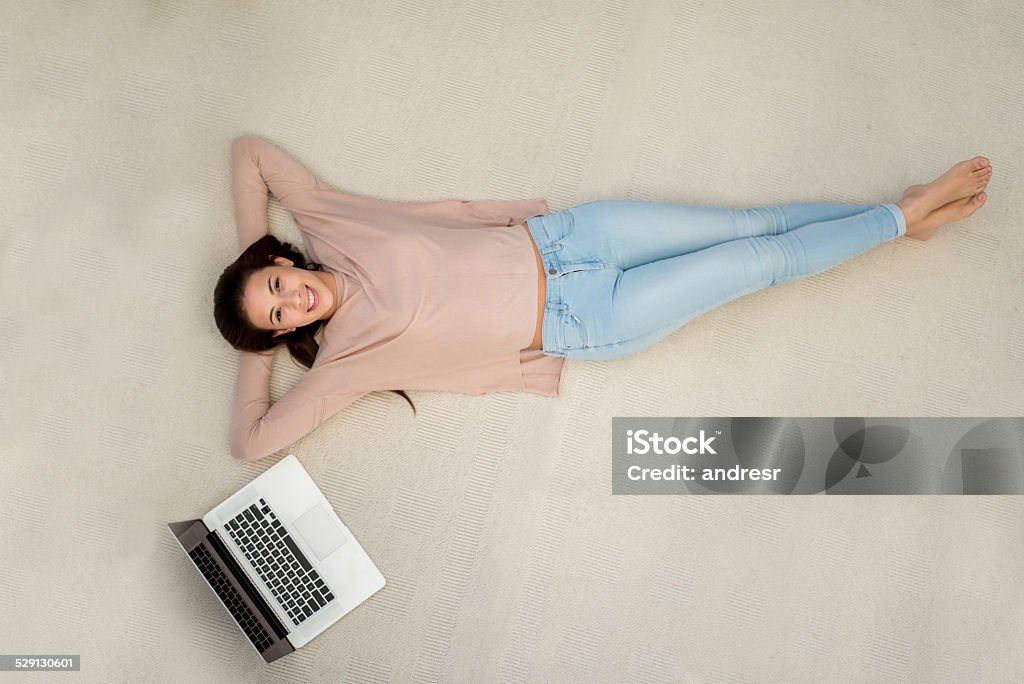 Woman relaxing at home Woman relaxing at home with a laptop next to her Lying Down Stock Photo