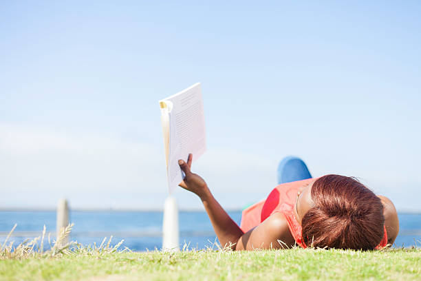 istock African female tourist lying on her back reading a book. 529131095