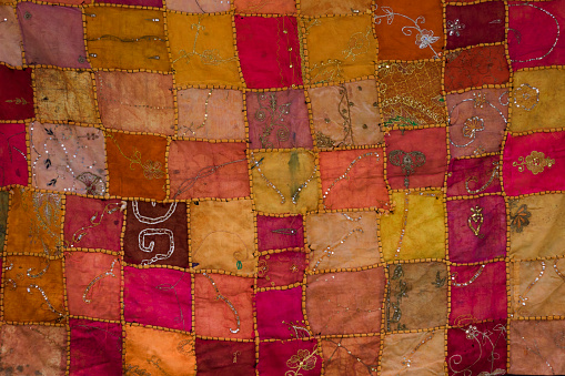 Middle eastern style patchwork background.The colors are dominantly red, orange and yellow.The parts are mostly square.Nobody are seen in frame.Horizontal composition.