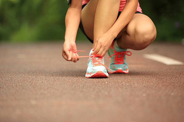 istock woman runner tying shoelaces on trail 529132449