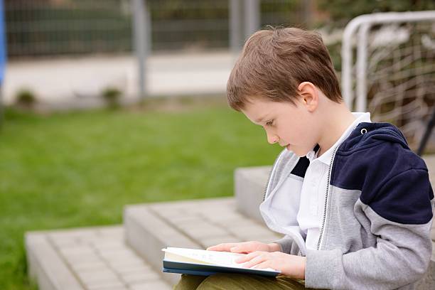 istock 7 year old boy reading a book on the terrace 529133614
