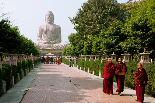 Bodhgaya, India - January 8, 2013: Group of Buddhist monks walking on the alley from the huge statue of Buddha on January 8, 2013 in Bodhgaya, India. Siddhartha Gautama attained enlightenment here at 500 BC.