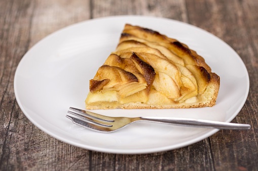 Slice of apple pie served on a plate with a dessert fork - studio shot