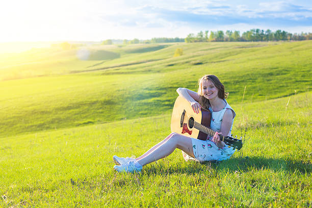 piękna młoda kobieta gra na gitarze o zachodzie słońca - sand dune audio zdjęcia i obrazy z banku zdjęć