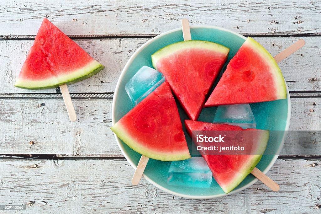 Watermelon slice popsicles on blue plate over rustic wood Watermelon slice popsicles on a vintage blue plate and rustic wood background Watermelon Stock Photo