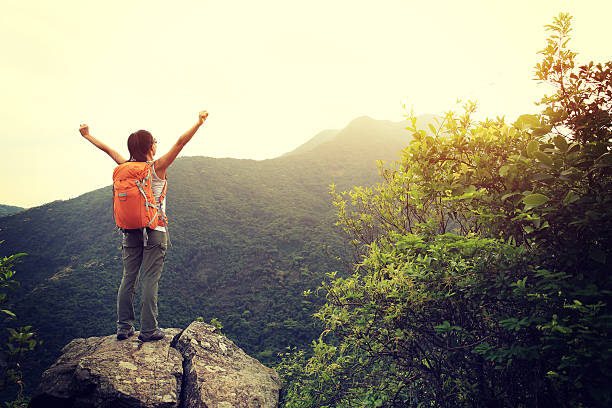 istock cheering woman hiker open arms on mountain peak 529143608