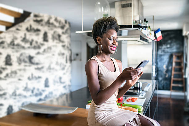 istock african french woman using the smartphone on the kitchen relaxing 529143768