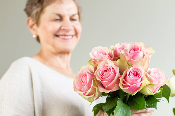 istock Older woman with pink roses 529143982