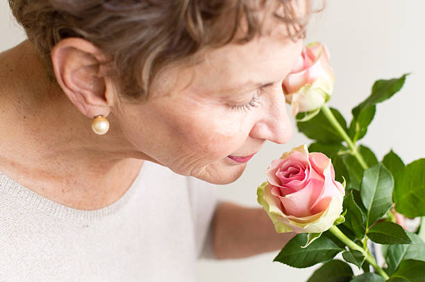 Older woman smelling pink rose