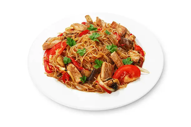 Asian food. Fried Thai glass Rice noodles with meat and vegetables. Chinese transparent glass rice vermicelli fried with meat, parsley and tomatoes. Korean funchoza cellophane noodles.