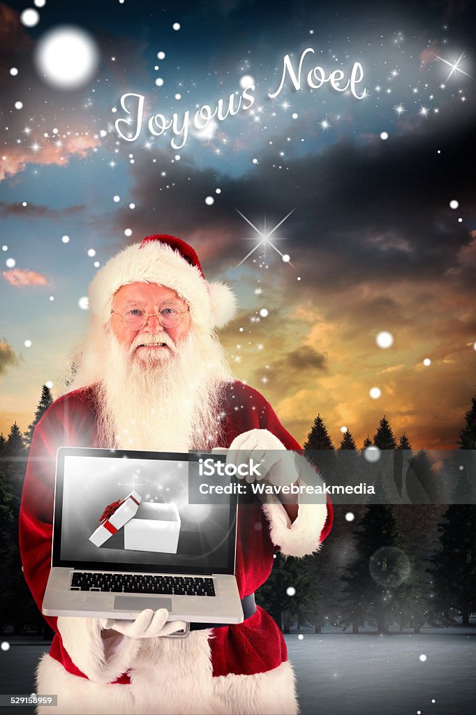 Composite image of santa claus presents a laptop Santa Claus presents a laptop against fir tree forest in snowy landscape 80-89 Years Stock Photo