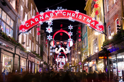London, United Kingdom - December 13, 2014: Crowds of Christmas shoppers in Carnaby Street, Central London. Long exposure at night of Carnaby Street, a pedestrianised retail district in London famous for it's fashion and lifestyle shops.