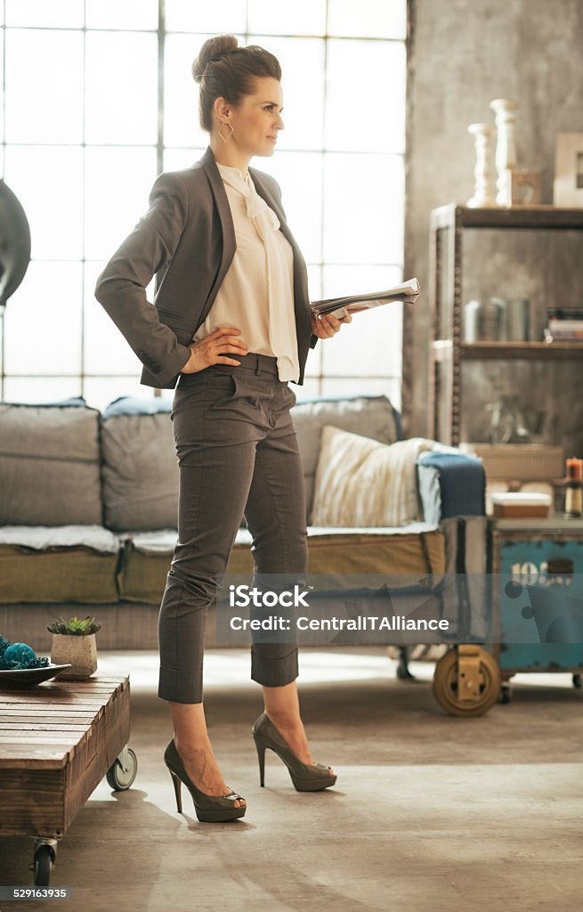 Mujer de negocios con una revista de pie en un apartamento tipo loft - Foto de stock de Adulto libre de derechos