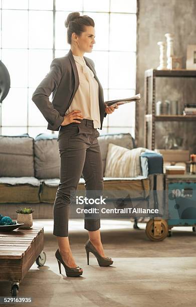 Mujer De Negocios Con Una Revista De Pie En Un Apartamento Tipo Loft Foto de stock y más banco de imágenes de Adulto