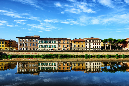 Pisa, Italy - September 18, 2013: Lungarno Galileo Galilei on the River Arno in Pisa, Italy. Old town buildings overlooing peaceful river.  No people.