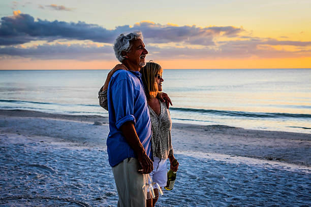 Active retirees enjoy the sunset on Siesta Key beach FL Siesta Key, FL, USA - December 15, 2012: Retired couple enjoy a romantic interlude with a bottle of wine and two glasses at sunset on Siesta Key beach Florida gulf of mexico photos stock pictures, royalty-free photos & images