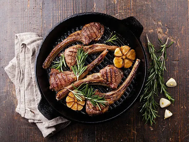 Roasted lamb ribs with rosemary and garlic on grill pan on dark background